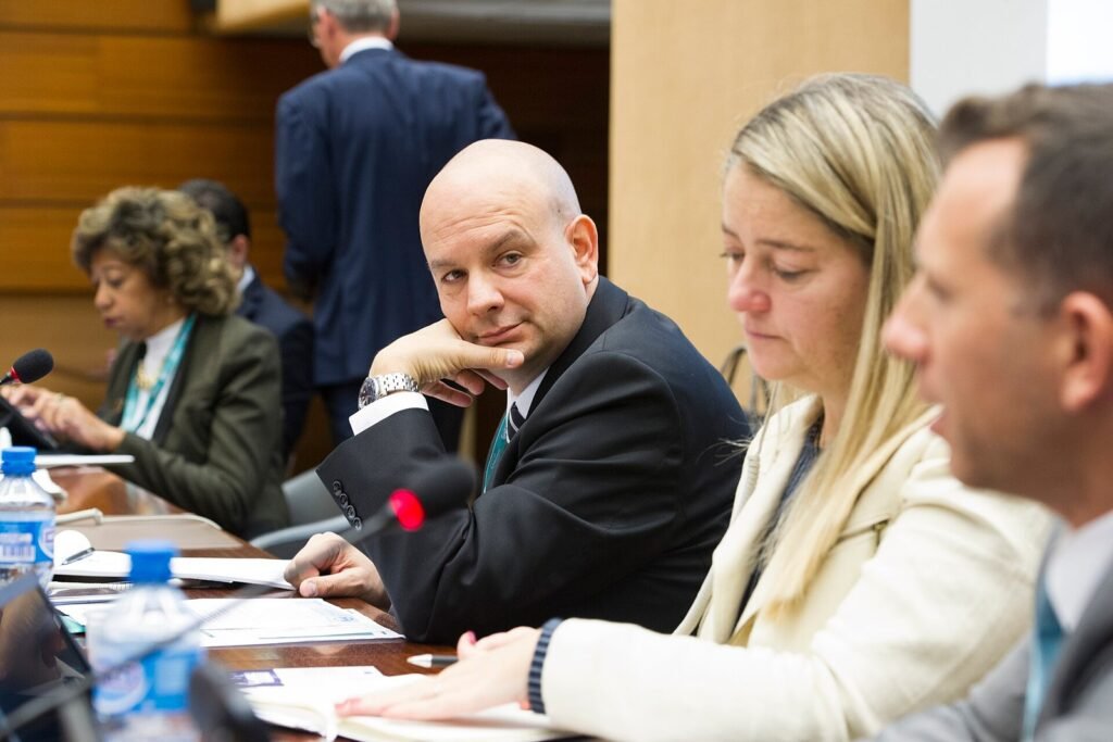 Participants seated at a conference table during an investment promotion workshop, with documents and microphones in front of them, in a formal meeting room setting