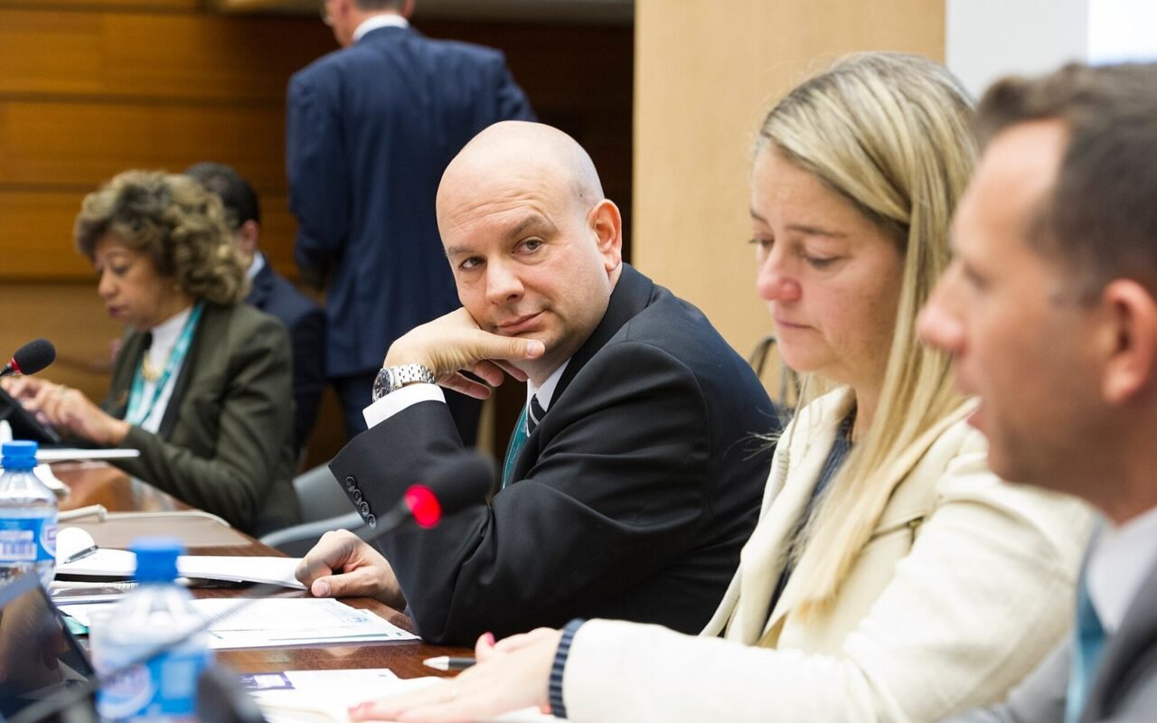 Participants seated at a conference table during an investment promotion workshop, with documents and microphones in front of them, in a formal meeting room setting